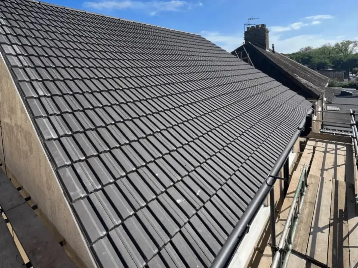 Sleek, uniform alignment of newly laid interlocking roof tiles looking down the roof pitch. Professional finish by Norfolk Exterior Solutions
